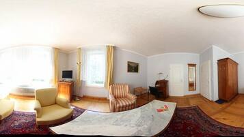 A panoramic view of a hotel room with a bed, a sofa, a chair, a desk, and a wardrobe.