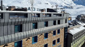 Un edificio moderno con un diseño arquitectónico único, que combina materiales de metal y piedra, y un cartel llamativo que indica que es un hotel.