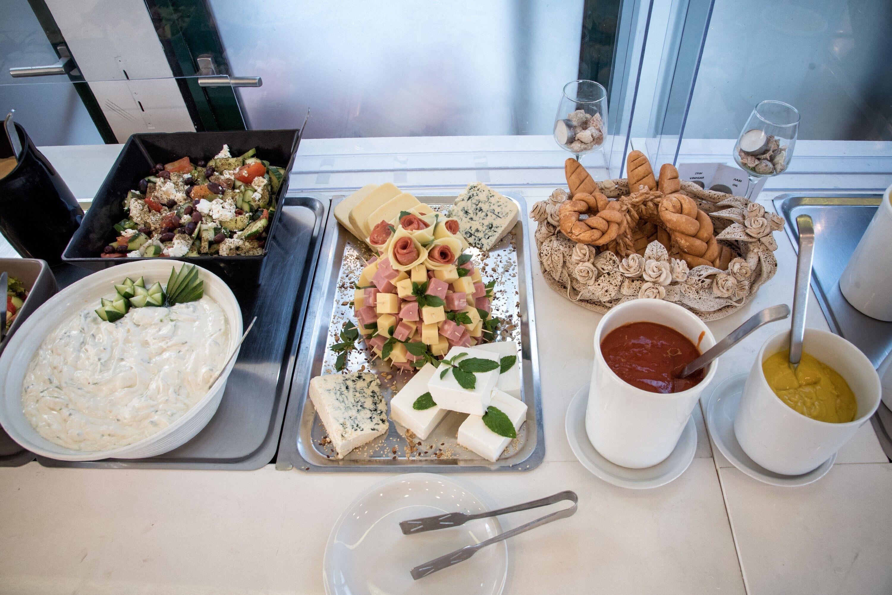 A buffet table with various food items including a salad, cheese, pastries, and dips.