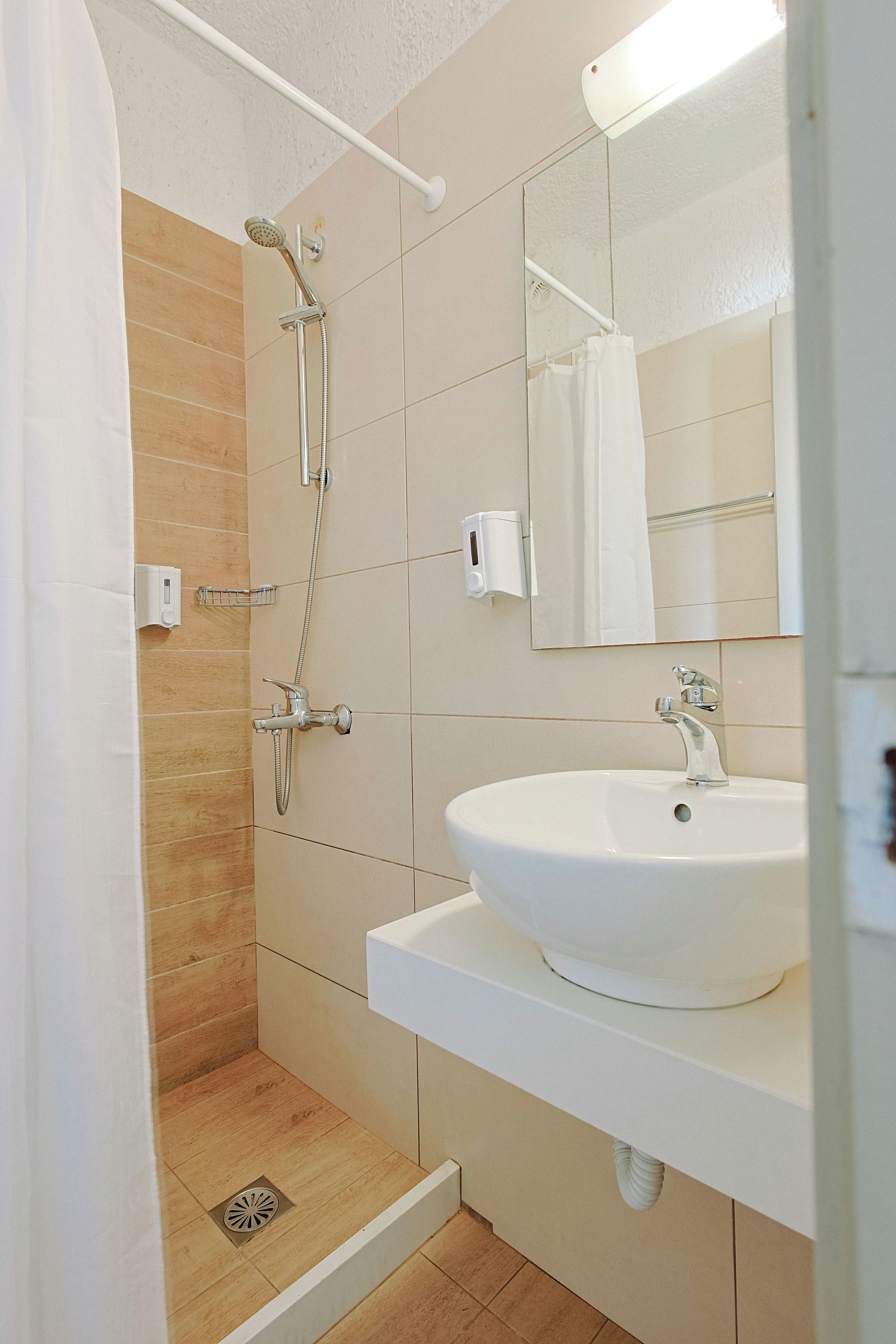 A modern bathroom with a shower, sink, and mirror.