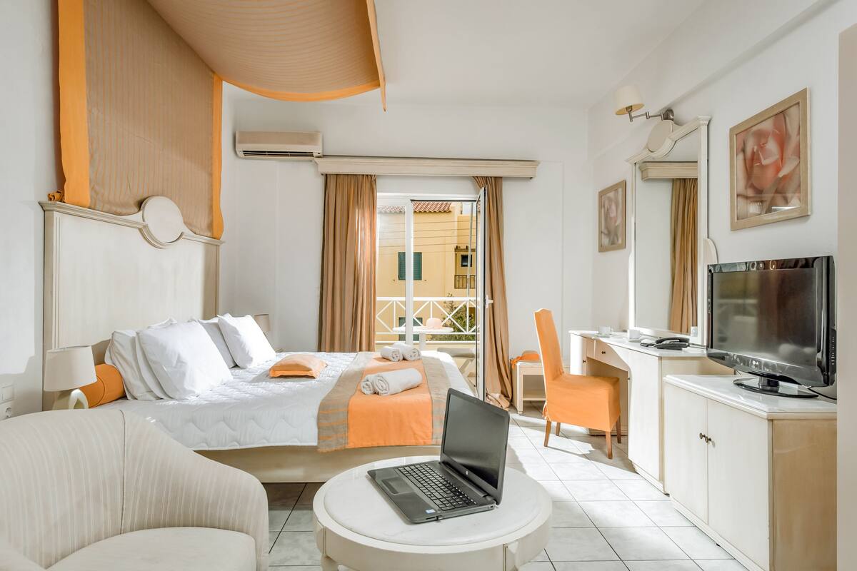 Une chambre d’hôtel avec un lit, un bureau avec un ordinateur portable, une télévision et une vue sur l’extérieur.