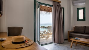 Ein Zimmer mit einem Holztisch, einer Couch, einem Sessel und einem Balkon mit Meerblick.