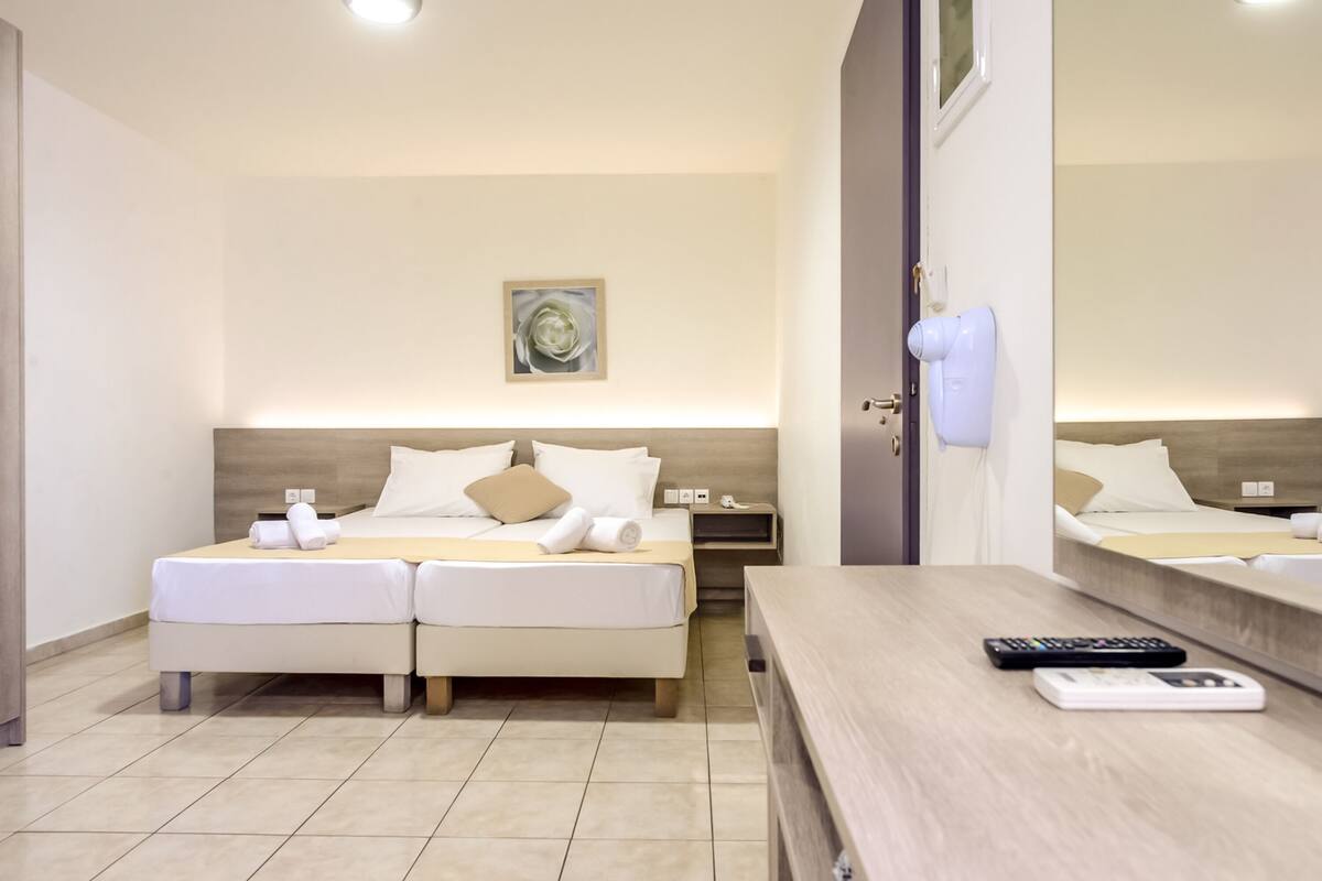 Une chambre d’hôtel avec un lit, des tables de chevet, un bureau et un miroir.