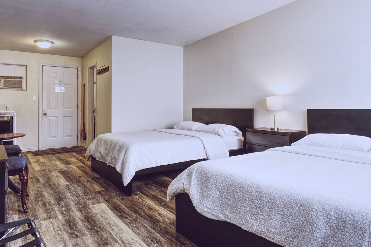 A hotel room with two beds, a desk, and a chair.