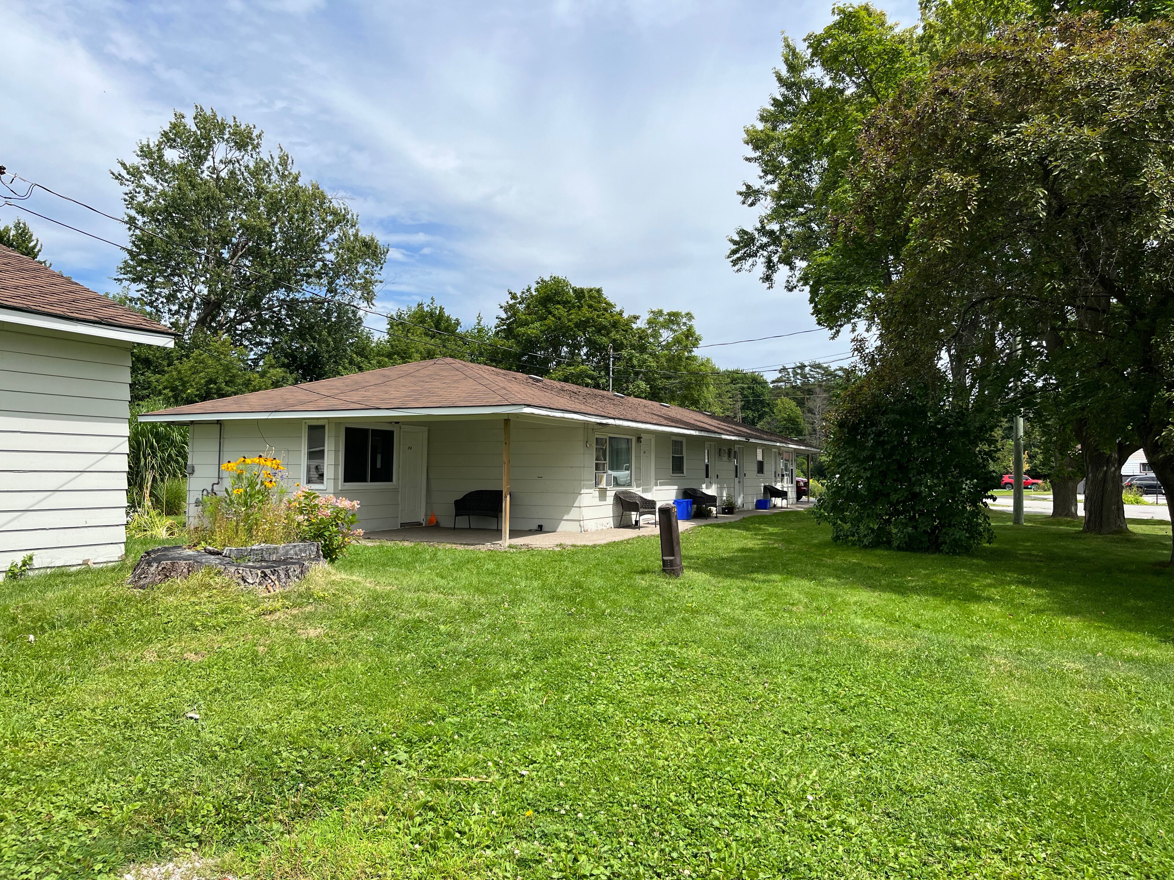 A single-story house with a porch, a small garden, and a lawn.