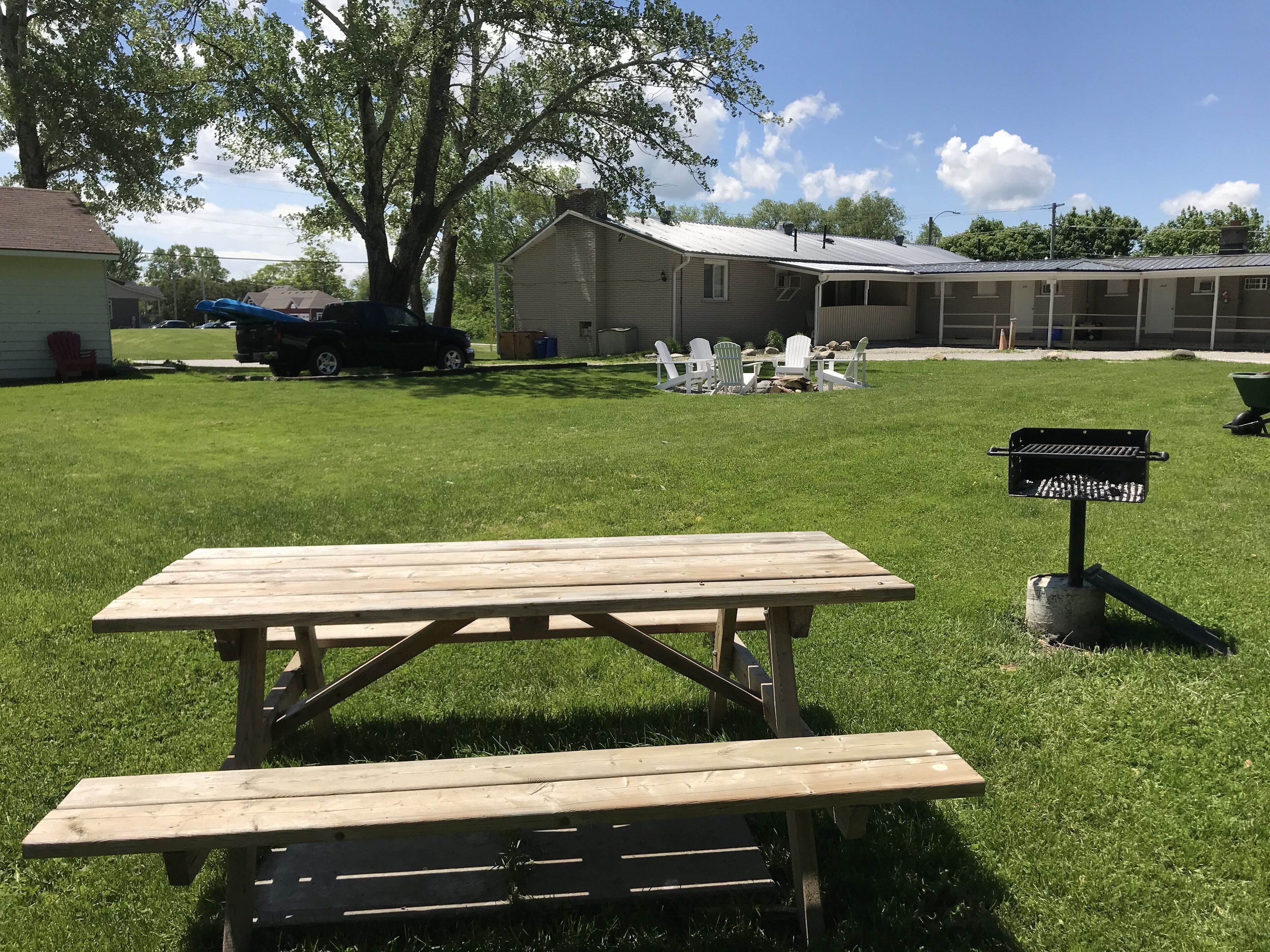 A picnic table in a grassy yard with a building in the background.