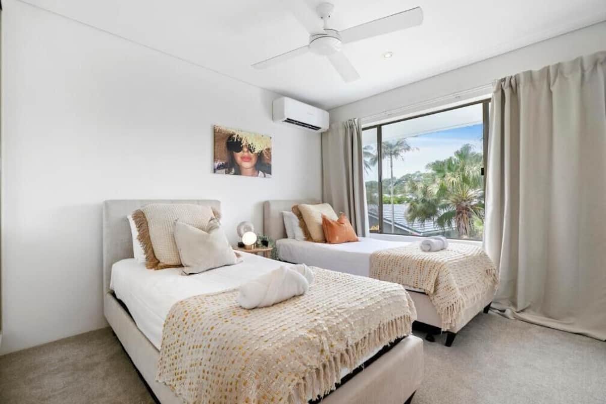 Une chambre d’hôtel avec deux lits, un ventilateur de plafond, un appareil de climatisation et une grande fenêtre avec des rideaux.