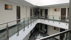 A multi-level interior with glass railings, doors, and artwork on the walls. - Hotel Gulnar (New Delhi)