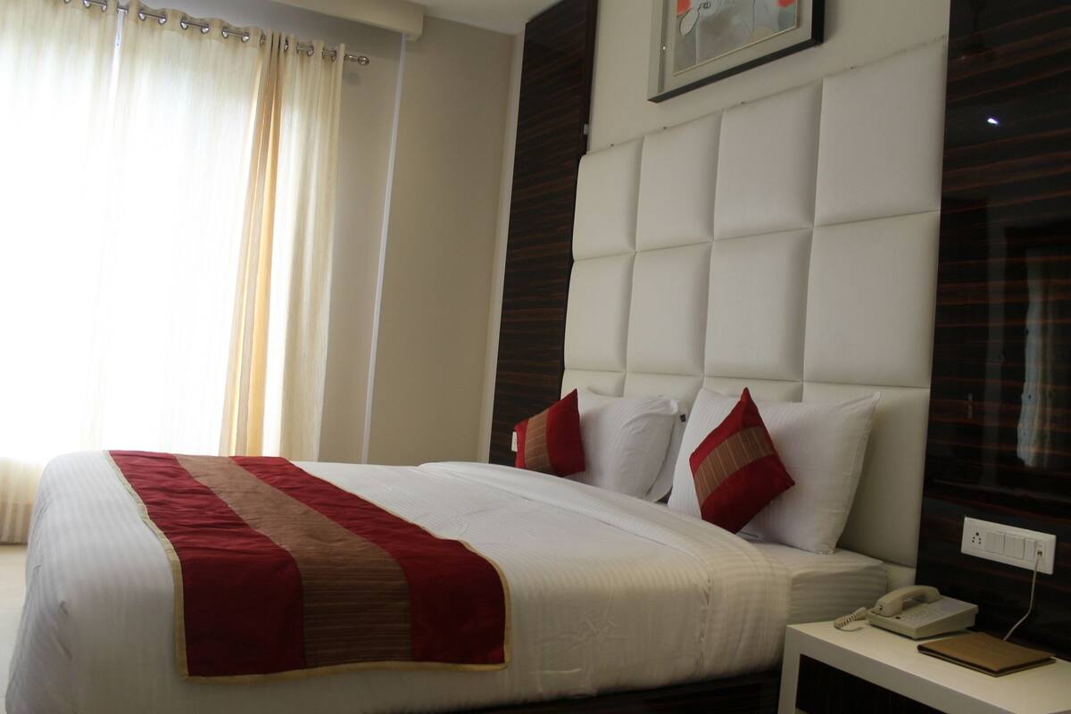 A hotel room with a large bed, a bedside telephone, and a nightstand.