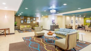 A hotel lobby with a reception desk, seating area with sofas and chairs, and a dining area with tables and chairs. - La Quinta Inn & Suites by Wyndham Floresville (Floresville)
