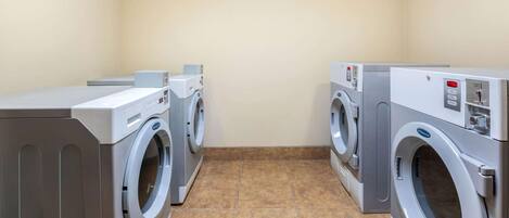 A laundry room with four washing machines and dryers, tiled floor, and plain walls.