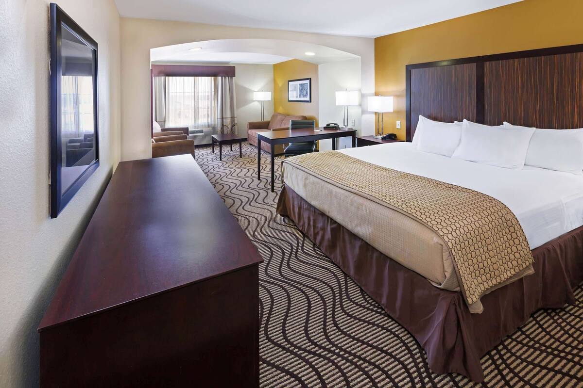 A hotel room with a large bed, a desk, a chair, and a TV.