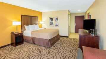 A hotel room with a bed, bedside tables, a TV, and a patterned carpet.