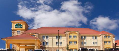A hotel with a red roof and a sign reading "La Quinta Inn & Suites".