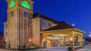 A La Quinta Inn & Suites building with a stone facade, a covered entrance, and a sign indicating the name and suite type. - La Quinta Inn & Suites by Wyndham Floresville (Floresville)