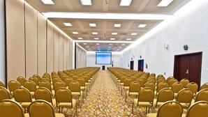 A conference room with rows of chairs, a carpeted floor, a projector screen, and a door. - Hotel Panamby São Paulo (São Paulo)