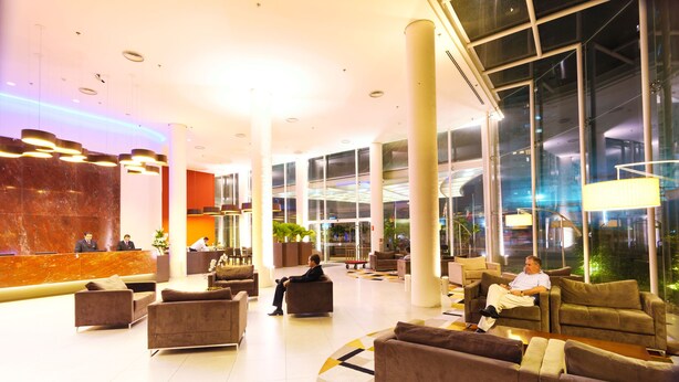 A spacious lobby with multiple seating areas, a reception desk, and large windows providing views of the outside. - Hotel Panamby São Paulo (São Paulo)