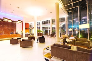 A spacious lobby with multiple seating areas, a reception desk, and large windows providing views of the outside.