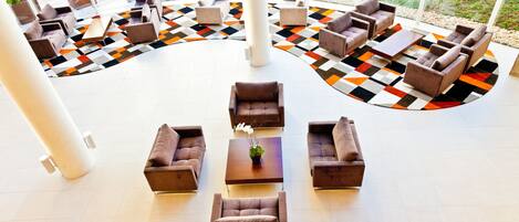 A spacious indoor area with multiple seating arrangements, including sofas and armchairs, arranged around a central coffee table.