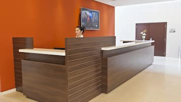 Un mostrador de recepción de diseño moderno, un televisor montado en la pared y una puerta al fondo.
