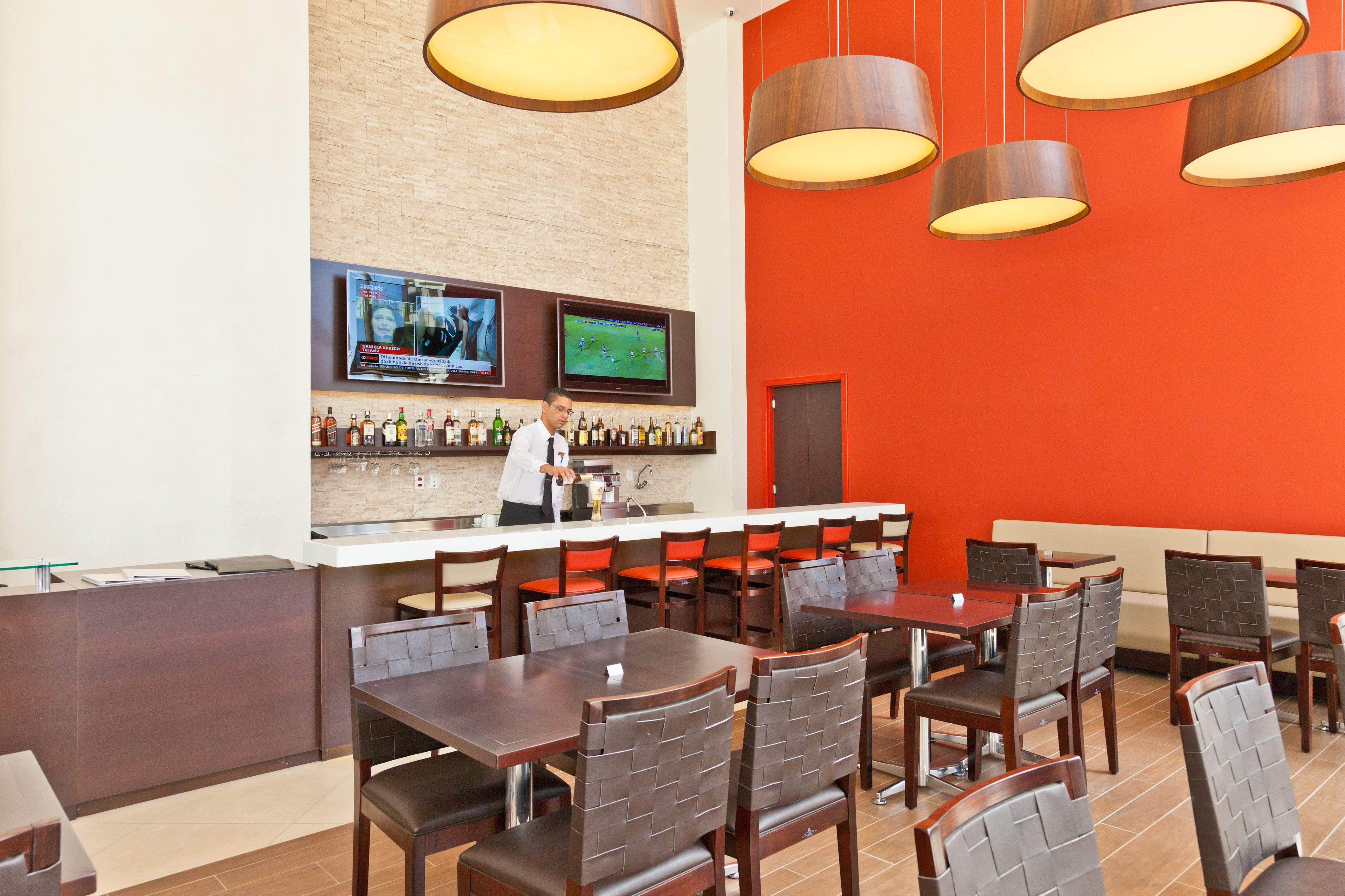 A restaurant with a bar area, multiple tables, and chairs.