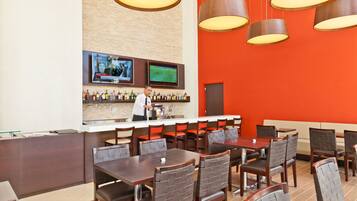 A restaurant with a bar area, multiple tables, and chairs.