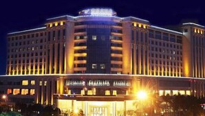 Un hotel grande de varios pisos con un estilo arquitectónico clásico, que presenta una entrada central y varios balcones.
