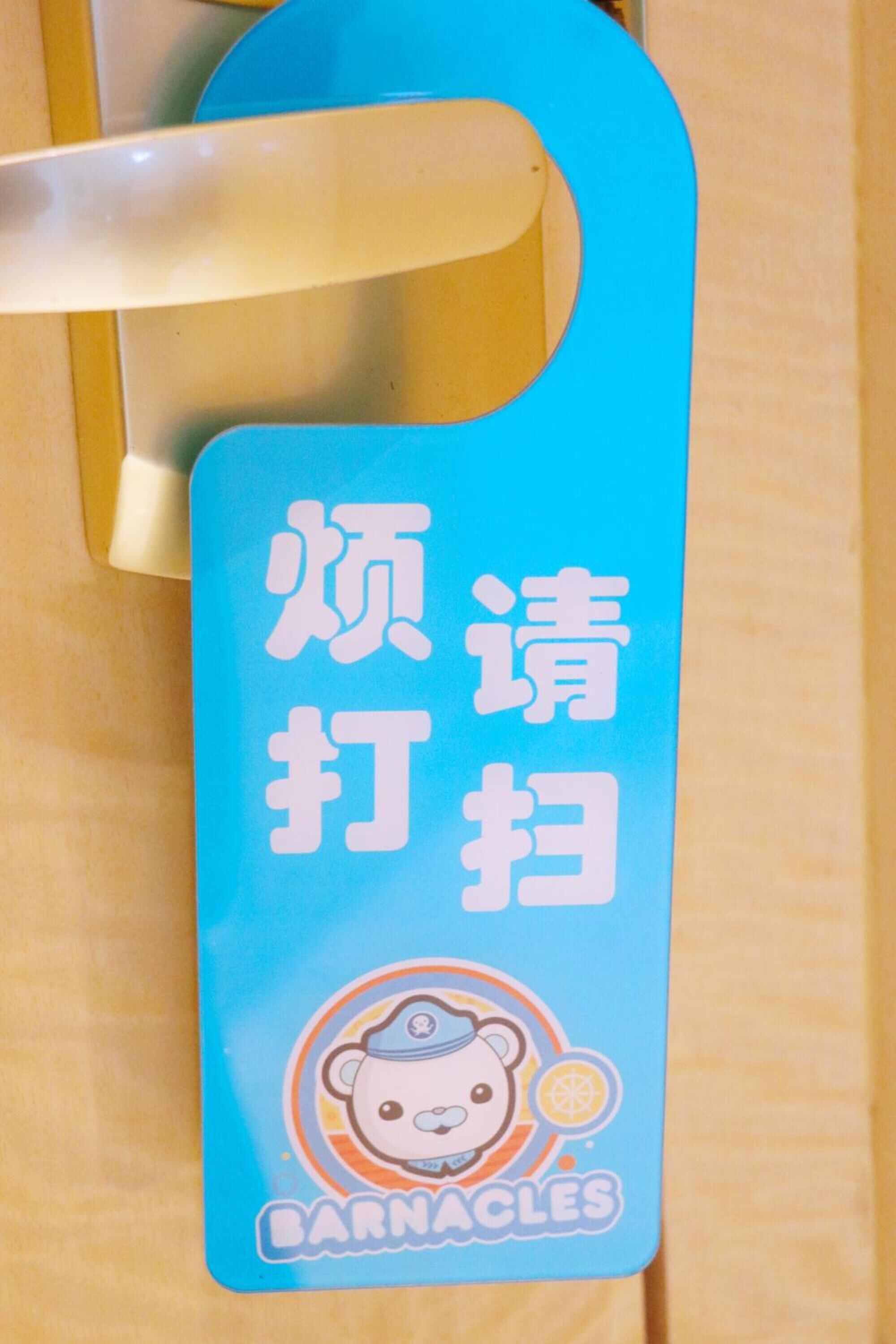 A blue tag with Chinese characters and a bear logo, attached to a door handle.
