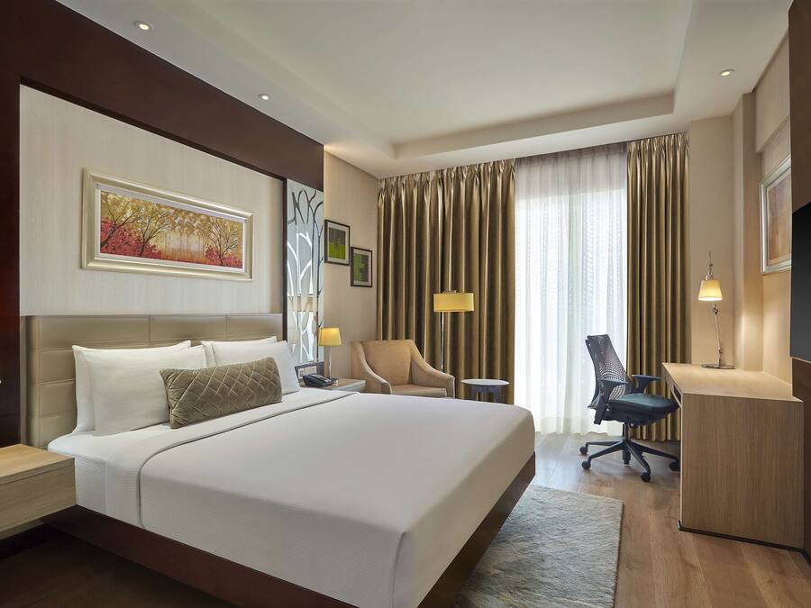 Habitación de hotel con una cama grande, un escritorio, una silla y un televisor.
