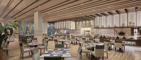 A spacious restaurant with multiple dining areas, wooden flooring, and a modern ceiling design.