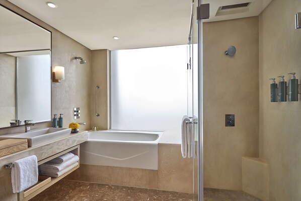 A modern bathroom with a large bathtub, a walk-in shower, and a vanity with a mirror and towel rack. - DoubleTree by Hilton Gurugram Baani Square (Gurugram)