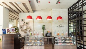A cafe with a modern interior, featuring a counter with baked goods and a display case with pastries. - DoubleTree by Hilton Gurugram Baani Square (Gurugram)