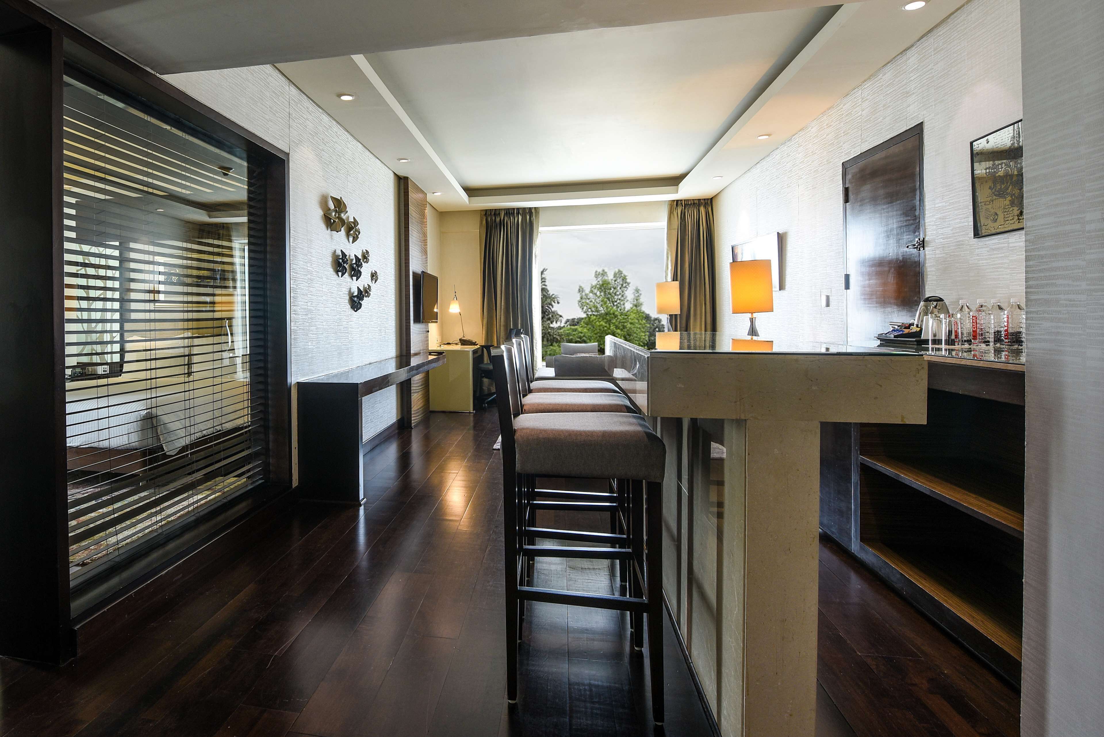 Un lobby moderno de hotel con zona de bar, asientos y vistas al exterior.
