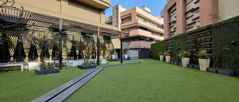 Un patio con césped artificial, zonas de estar y plantas en macetas.