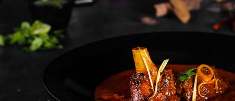 A dish with meat and bone garnish on a dark plate.