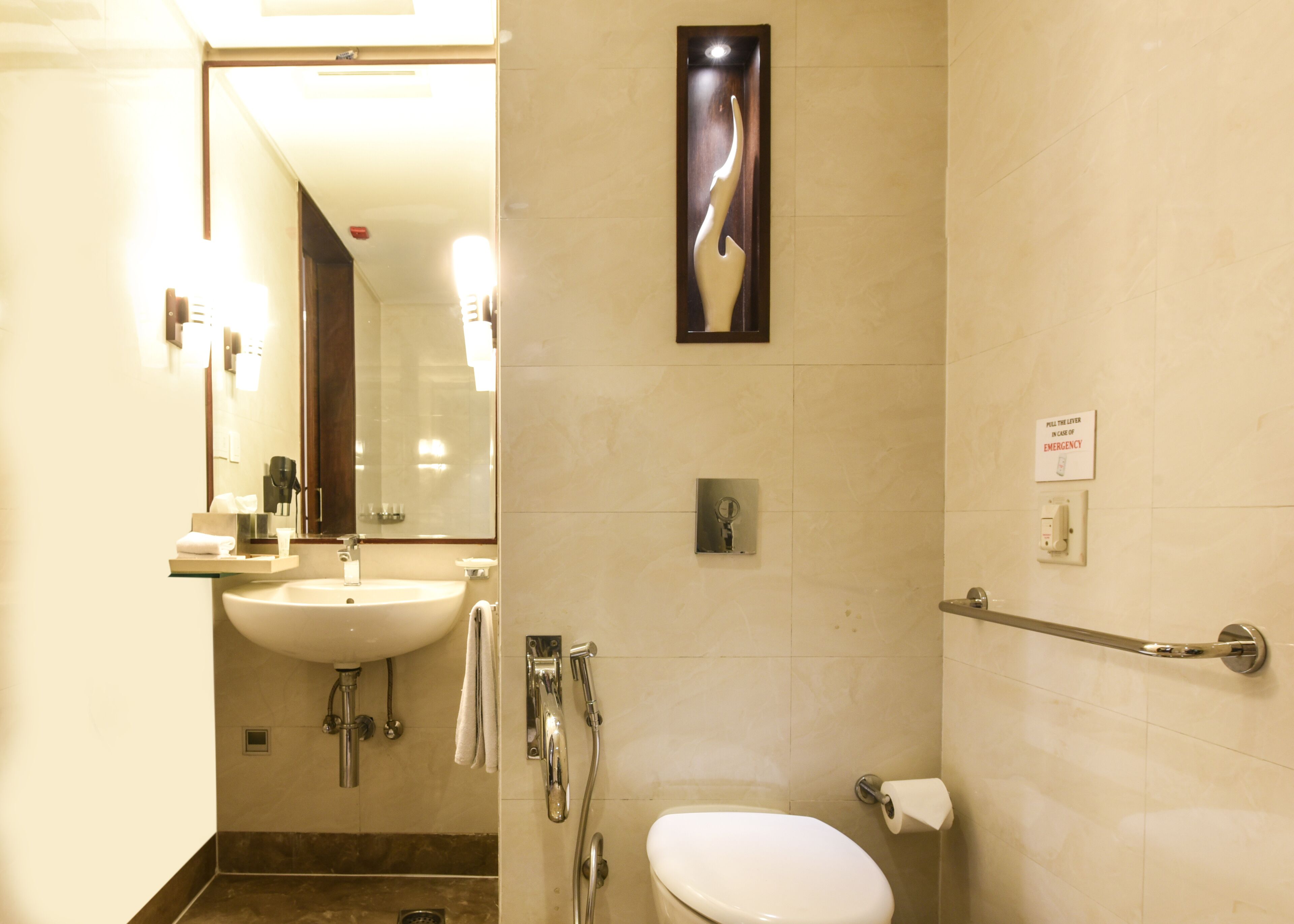 Baño con lavamanos, espejo, inodoro y baranda.