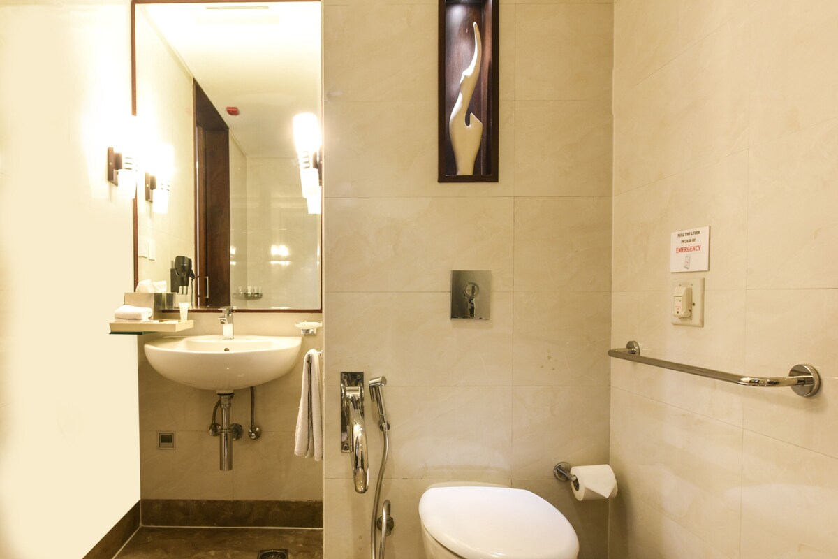 Baño con lavamanos, espejo, inodoro y baranda.