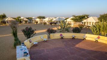 A desert resort with outdoor seating areas, tents, and sparse vegetation.