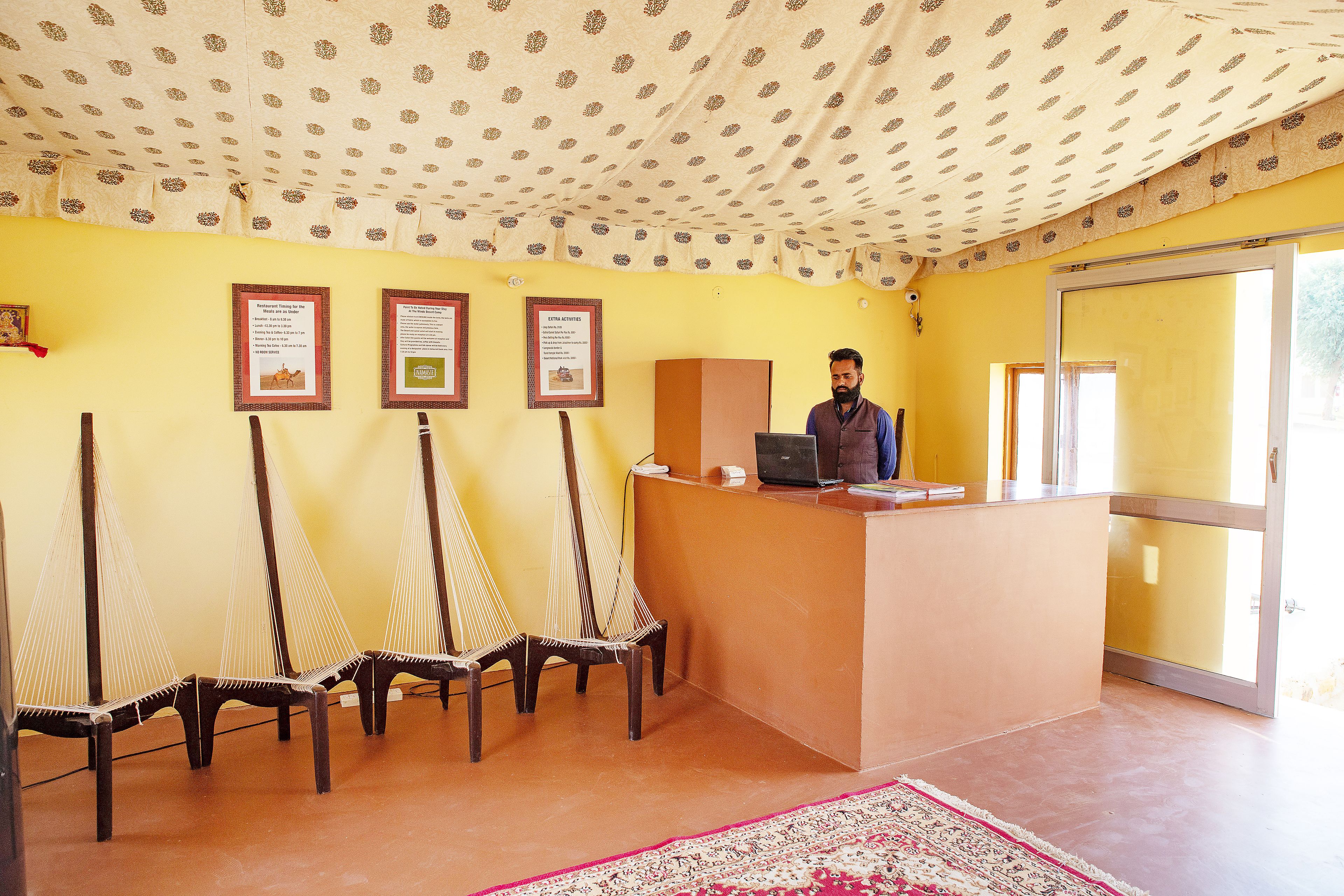 A reception area with a desk, chairs, framed certificates on the wall, and a patterned ceiling.