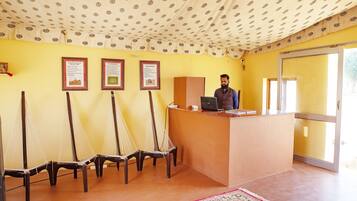 A reception area with a desk, chairs, framed certificates on the wall, and a patterned ceiling.