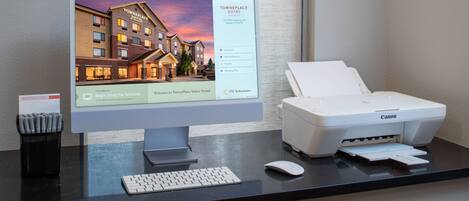 Ein Schreibtisch mit einem Monitor, der ein Hotel zeigt, einem Drucker, einer Tastatur und einer Maus.