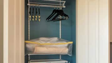 Un vestidor con estantes metálicos, una barra para colgar ropa y un contenedor de almacenamiento.