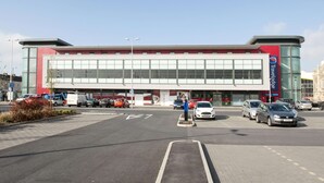 A modern building with large windows, a Travelodge sign, and a parking lot with cars. - Travelodgellanelli Cross Hands (Llanelli)
