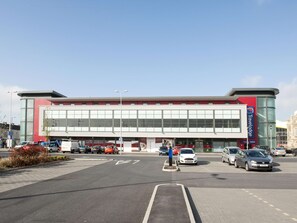 A modern building with large windows, a Travelodge sign, and a parking lot with cars. - Travelodgellanelli Cross Hands (Llanelli)