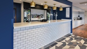 A reception area with a white counter, blue walls, and a patterned floor. - Travelodge Woking Central (Woking)