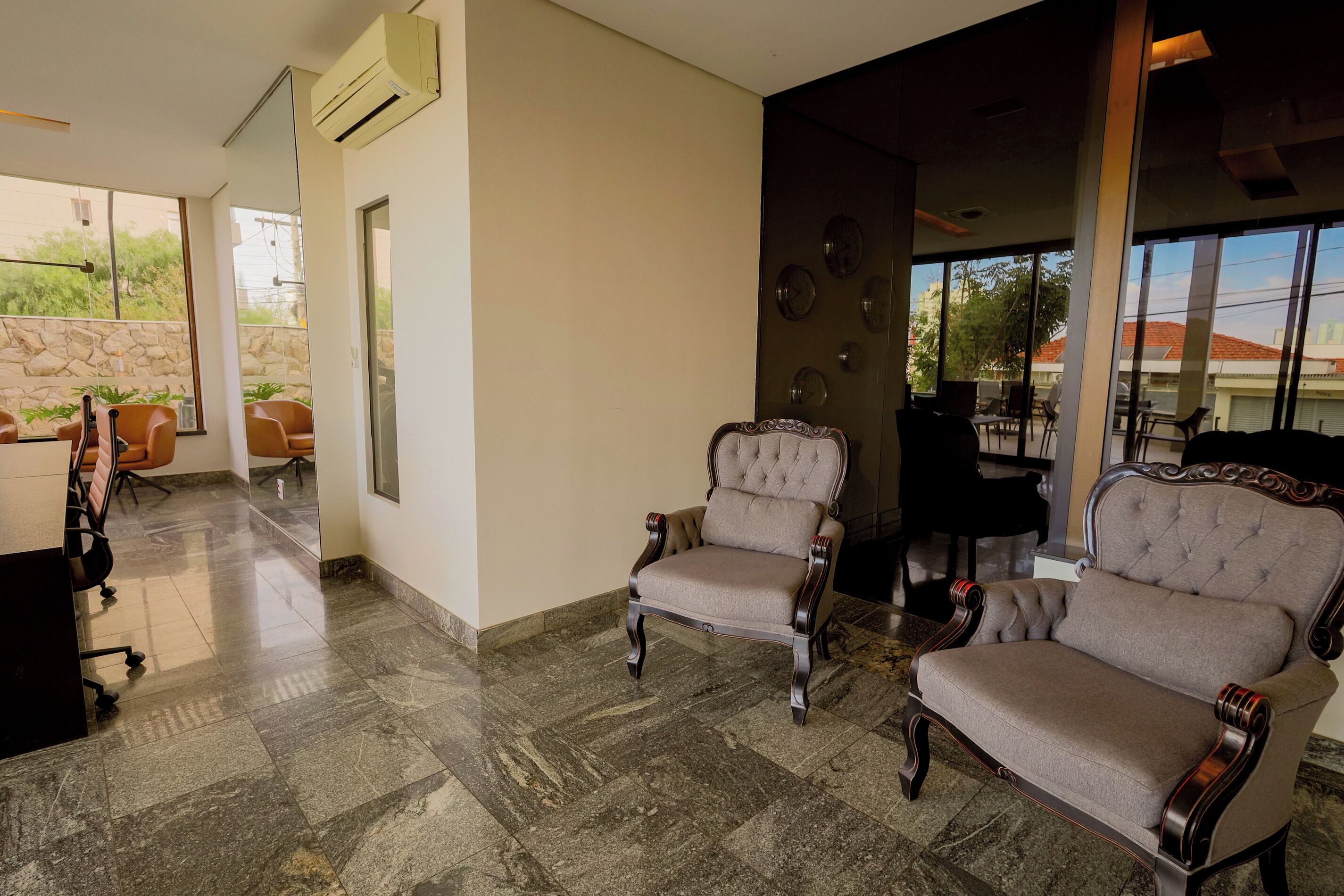 A lobby with two upholstered armchairs, a stone wall, and a tiled floor.