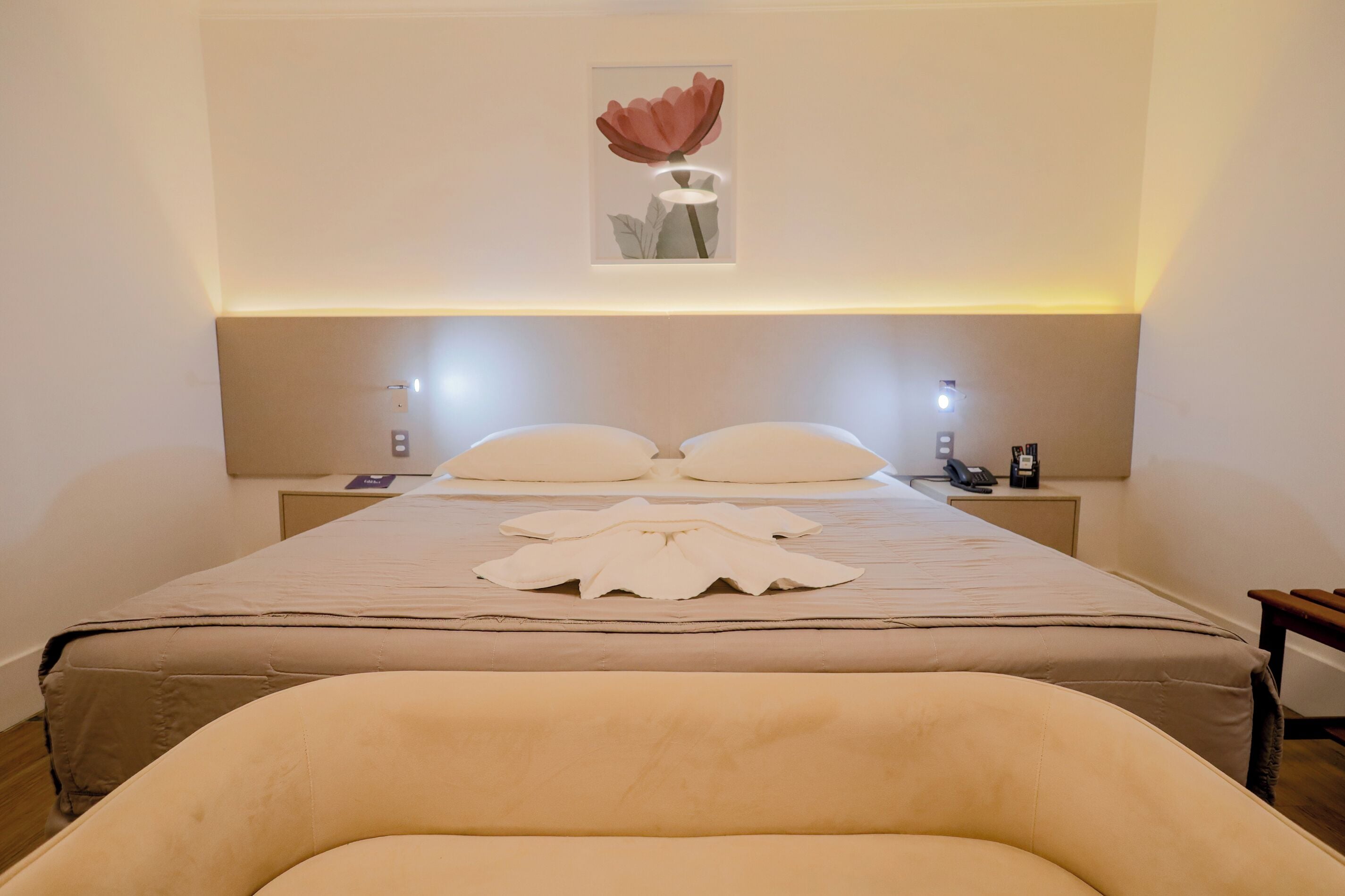 A neatly made bed with a large pillow, a bedside table with a lamp, and a framed picture on the wall.
