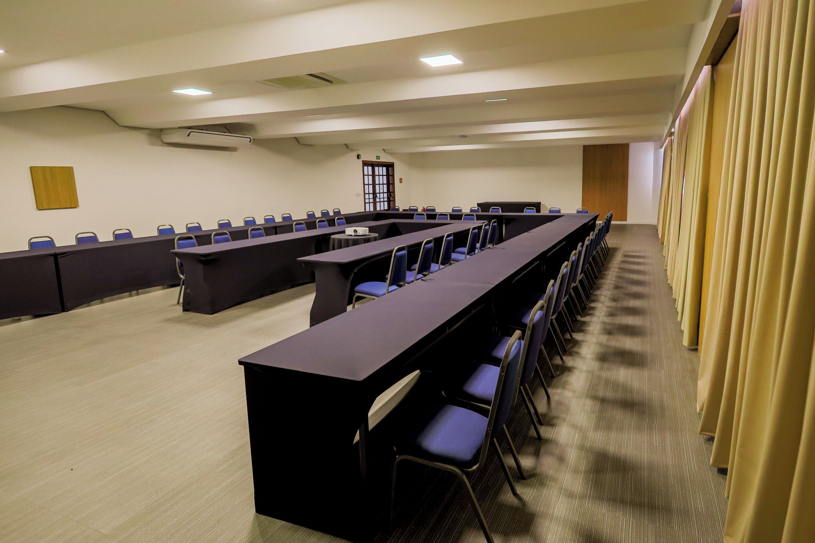 Una sala de conferencias con una mesa larga, sillas y un proyector.