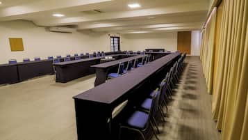 Una sala de conferencias con una mesa larga, sillas y un proyector.