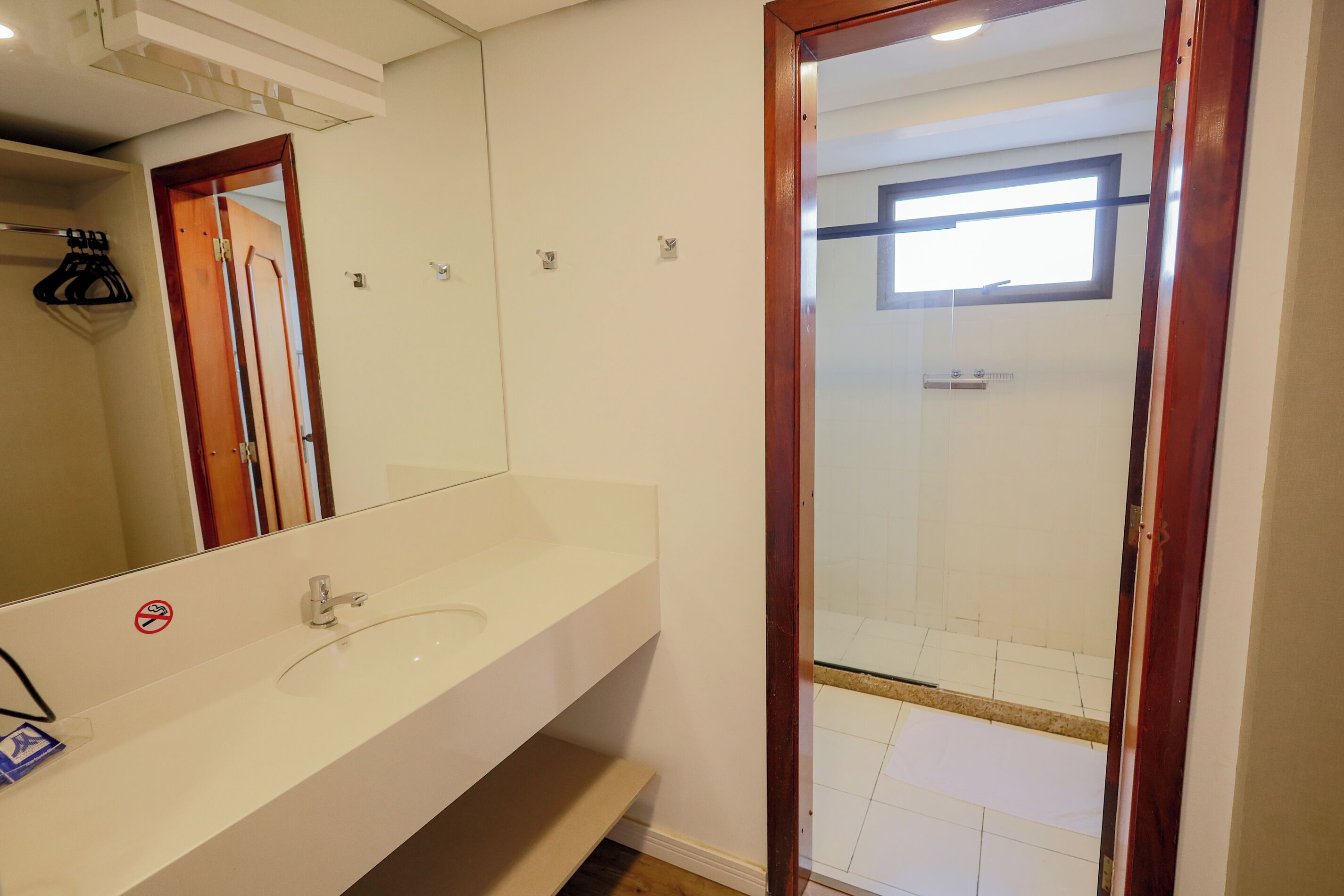 A bathroom with a white sink, a mirror, and a shower area visible through a glass door.